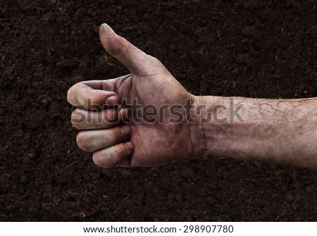 Dirty hand of a man with thumbs up isolated on fertile soil