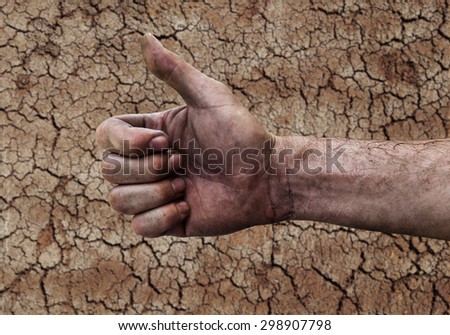 Dirty hand of a man with thumbs up isolated on soil