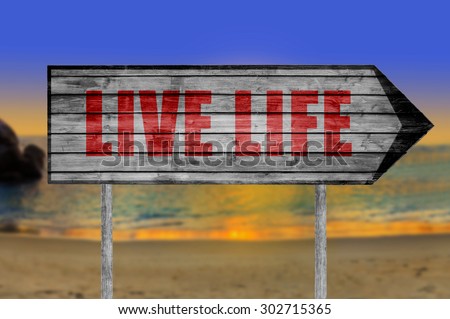 Red Live Life wooden sign with a beach on background