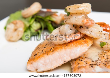 Grilled salmon topped with a creamy white sauce served with spring greens and shrimp