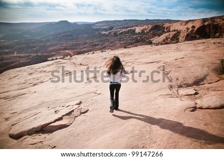 Athletic beautiful  woman running in desert rock with mountains in the background