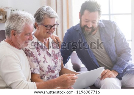 family team at work at home sit down on the sofa. smile and have fun working on a laptop together. mother father and son aged senior use technology and internet home. cheerful caucasian people modern