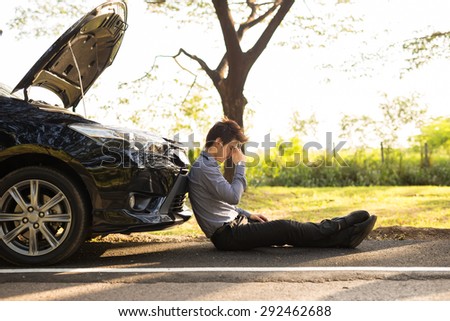 Full length of businessman with hands on head sitting by broken down car at countryside