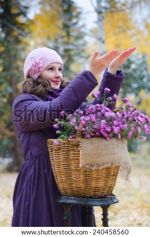 The girl in the Park, with a basket of flowers, catch the first snowflakes hands