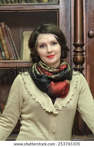 A woman in an antique library, on the background of the bookcase.