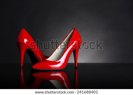 Red heels on black background with light spot.