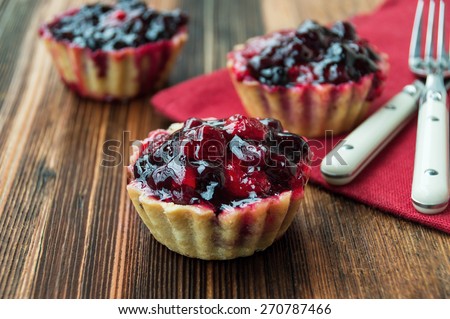 three sand-cakes with fruit-berry filling on a wooden textured table