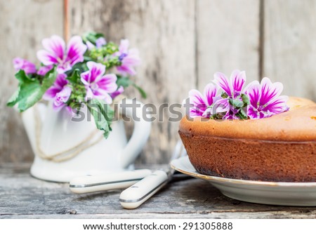 homemade biscuit cake decorated with flowers on rustic wooden table