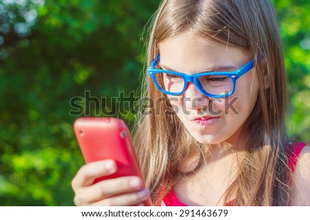 cute girl skeptical wrinkles her nose and looks at the phone screen