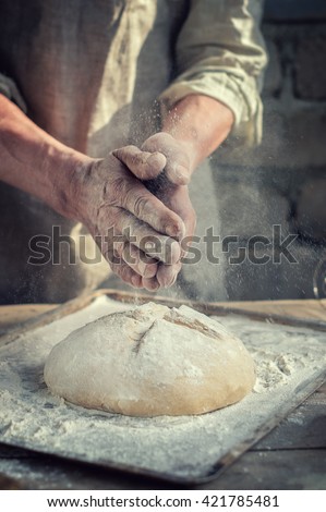 man Baker and his hands over the bread from whole wheat flour (to oven). flour, rustic style
