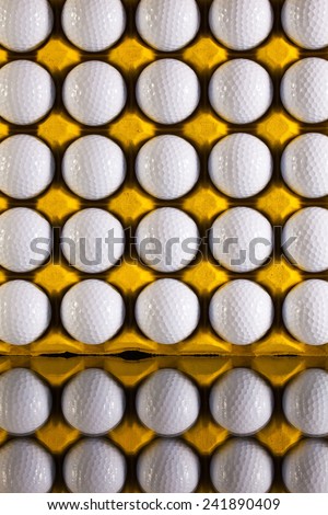 Golf balls in paper carton for eggs on a glass desk