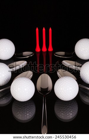 Teaspoons and golf equipments on the black glass desk