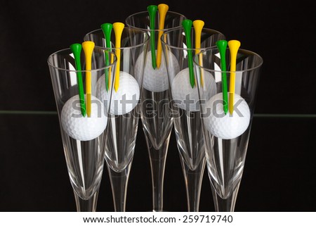 Five glasses of champagne and white golf balls on the glass plate
