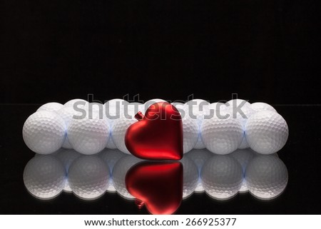 White golf balls and red heart on a glass plate