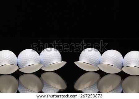 Six spoons and golf balls on a black glass desk
