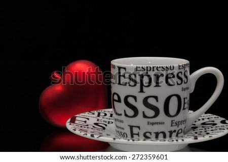 One empty coffee cup and red heart on a black glass desk