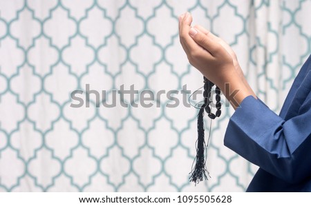 Young muslim boy prayer during holy month of Ramadhan with rosary beads in hand.