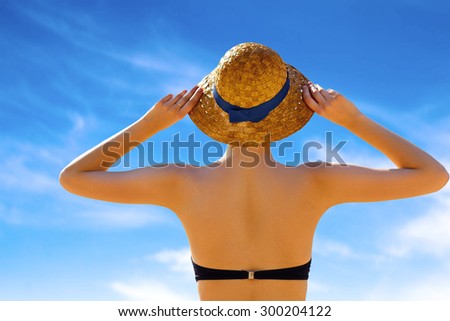 Rear view young woman in sun hat standing and tanning