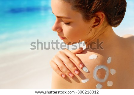 Portrait of gorgeous woman in bikini with the drawn sun on a shoulder at beach