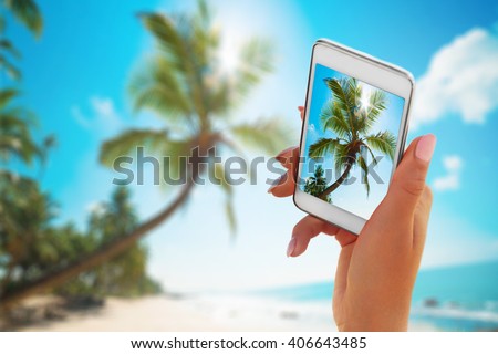 Close up hand holding smartphone on summer beach. technology, travel, tourism, communication and people concept