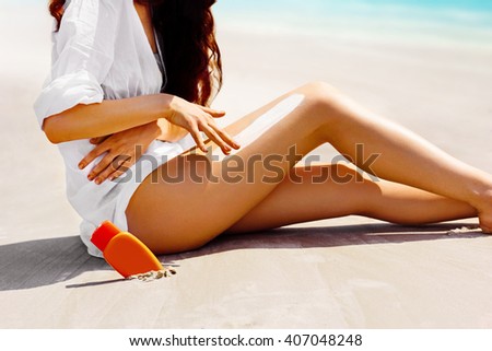 Closeup on female hand applying sun screen creme on leg