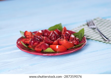 Salad with strawberries and tomatoes on a plate. Blurring background.