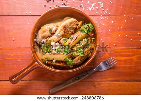 Country style potatoes and chicken served with parsley and garlic on a wooden brown background