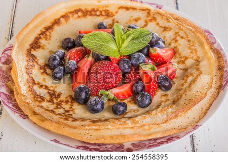 Homemade crepes with berries and fruit on a white background