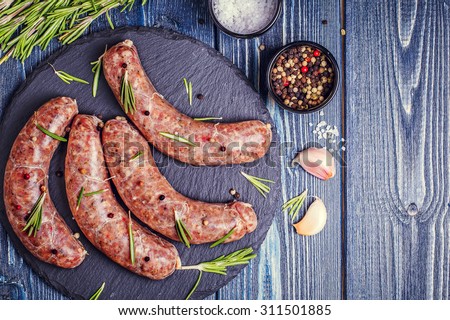 Raw sausage of beef and pork with spices on dark background.