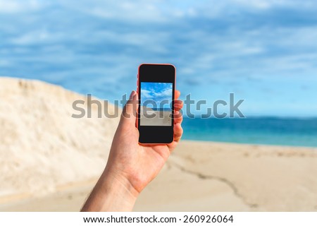 Male hand taking photo of seashore for instagram