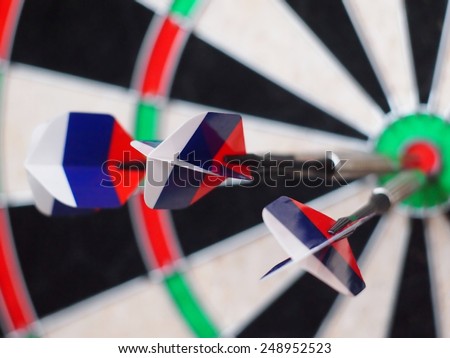 three arrows darts colors of the Russian flag hit the bull eye  / partly out of focus, top view from an angle
