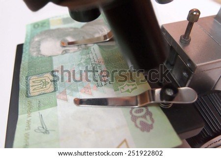 Ukrainian money under a microscope / partially out of focus, focus on the coat of arms of Ukraine