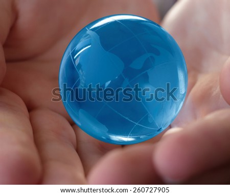 world, earth, planet, business concept - blue glass earth  globe in the hands