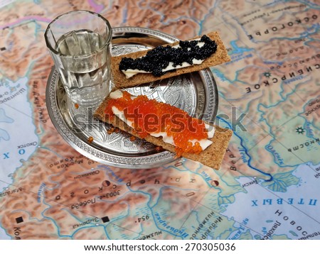 silver plate with black and red caviar and glass of vodka on a background of old maps of Siberia