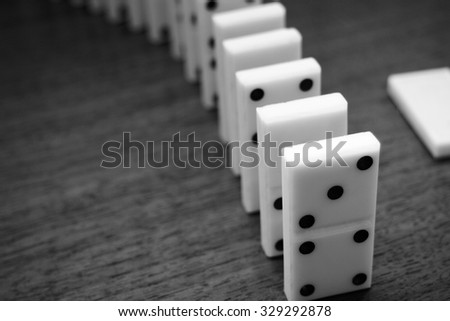 Domino, black and white / partly out of focus, focus on the first domino