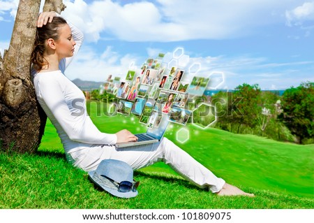 Portrait of young happy woman sharing her photo and video files in social media resources using her modern laptop. Outdoors at beautiful idyllic place.