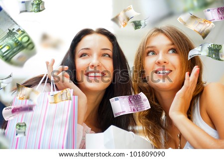 Group of beautiful shopping women with bags and smiling. Money flying around them. Spending money non stop concept