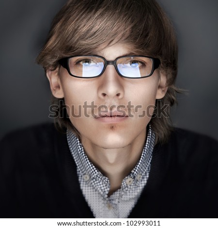 Portrait of young esquire man with smart and wise look. Looking at camera like at monitor. Reflection of screen of his laptop at eyeglasses