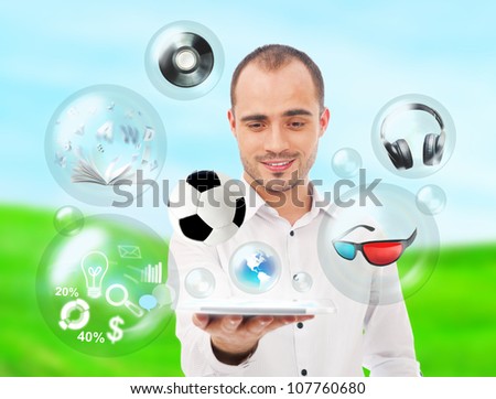 Adult handsome man holding tablet computer. Icons of different object are flying around. All multimedia in one mobile gadget concept