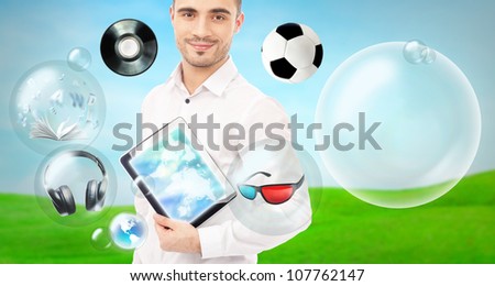 Adult handsome man holding tablet computer. Icons of different object are flying around. All multimedia in one mobile gadget concept