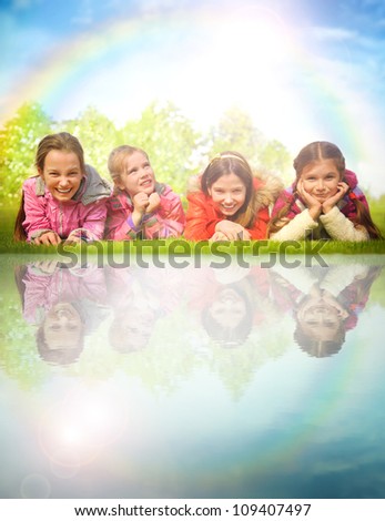 Children laying on grass near water. Family and friends picnic in spring or autumn park