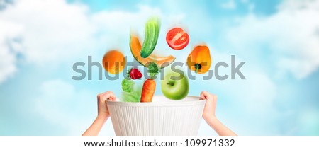 Hands are holding basket against sky background, vegetables, fruits and berries are falling into this basket. Online grocery store concept. Wealth concept. Healthy food concept