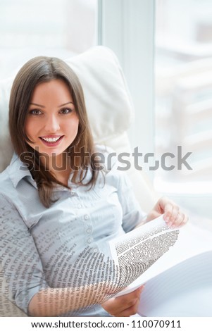 Young beautiful woman sitting on her armchair and reading book. Letters are flying from book to camera. Easy education concept