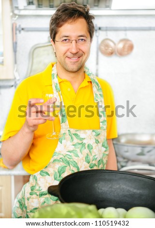 Handsome mature man is cooking at his kitchen.