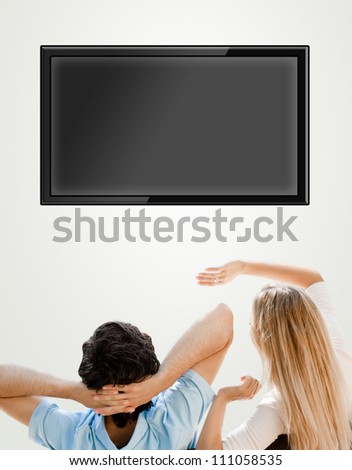 Young couple watching tv. Photo from behind. Lots of copyspace