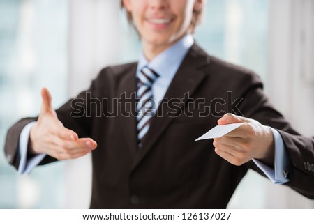 Business man holding a blank business card indoors at his office