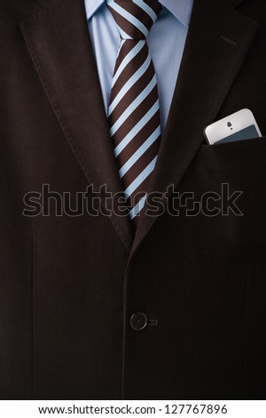 Closeup of torso of confident business man wearing elegant suit and mobile phone at pocket