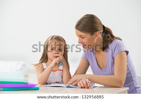 Mother and daughter at home. Mom teaching little girl to draw and write