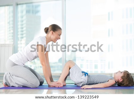 Healthy morning stretching - woman with son doing gymnastic exercise at home