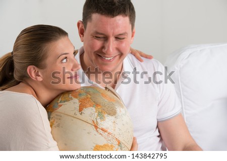 Portrait of happy romantic couple sitting together at home with globe planning their vacation and trip. Travelling concept